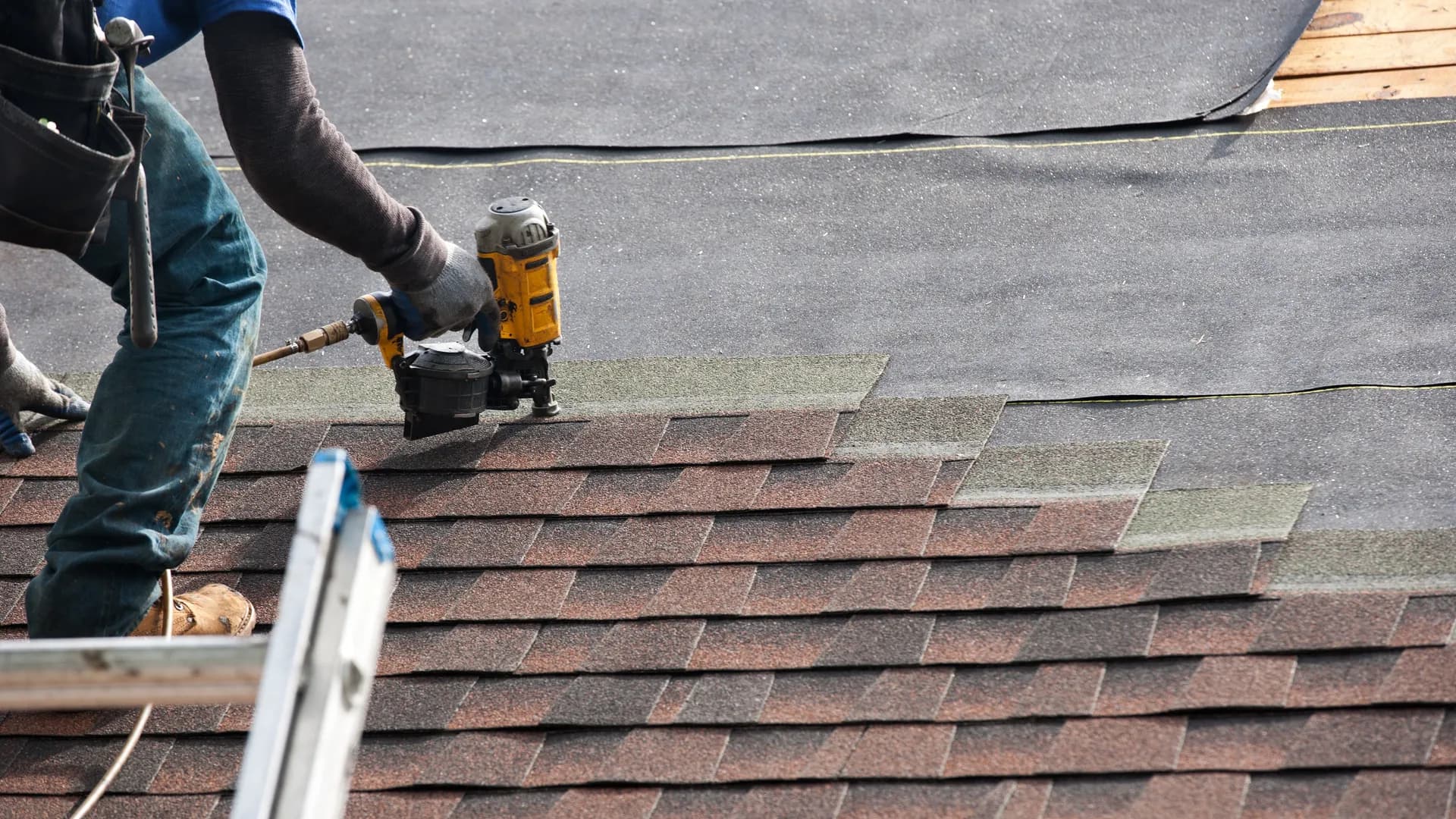 Roofing crew installing asphalt shingles on Utah residential home, action shot with blue sky background